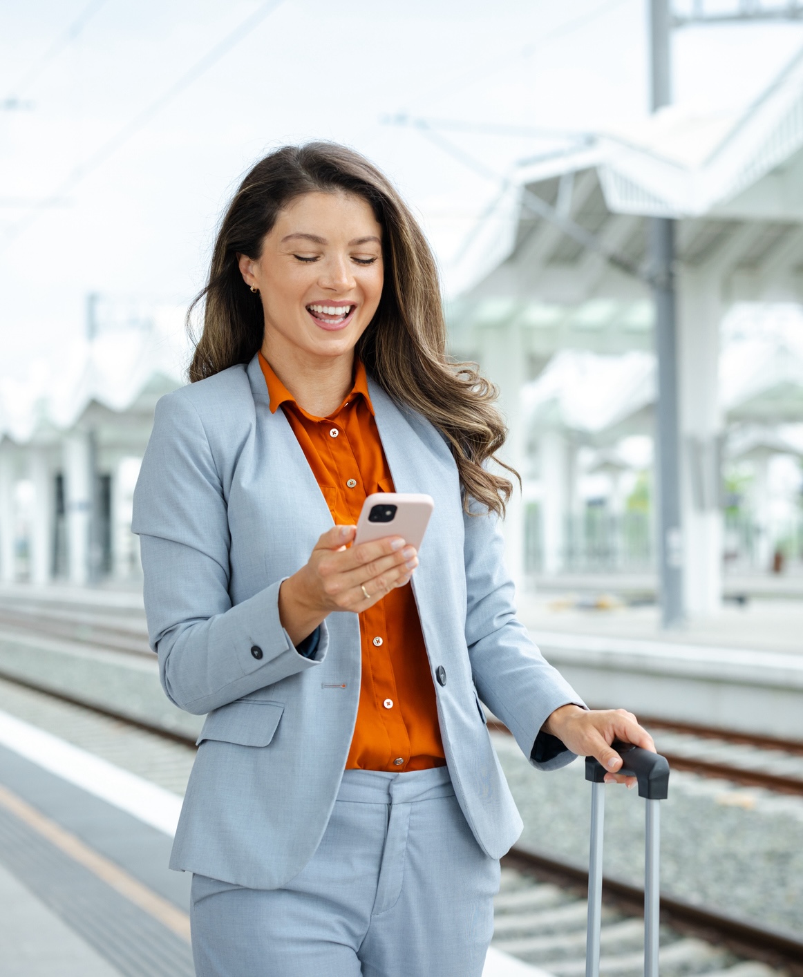 Beautiful business woman using the phone at the train station